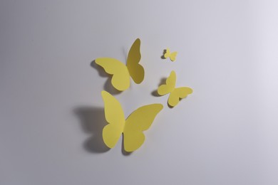 Photo of Yellow paper butterflies on light background, top view