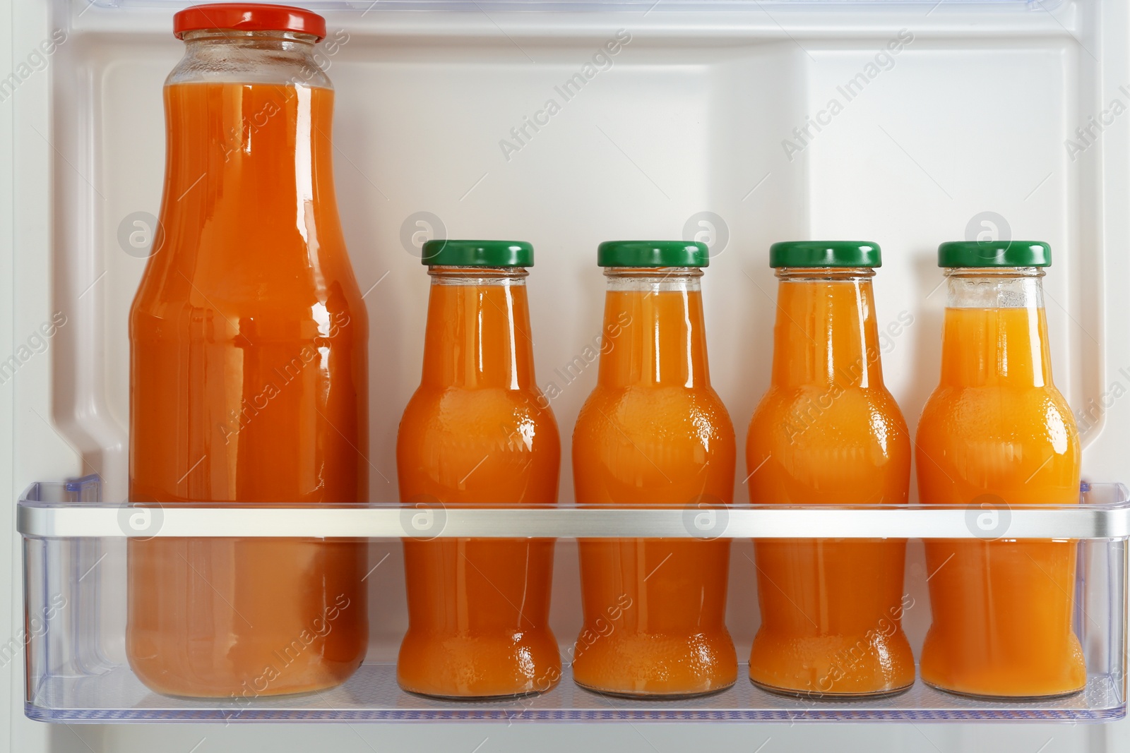 Photo of Bottles of juice on shelf in refrigerator