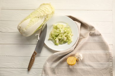 Photo of Fresh Chinese cabbage, green onion, lemon and knife on white wooden table, flat lay