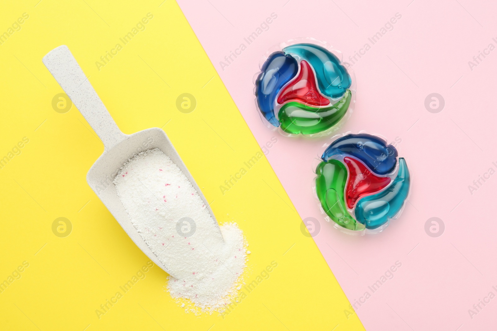 Photo of Laundry capsules and scoop of washing powder on color background, flat lay