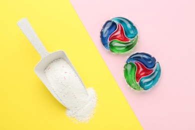 Photo of Laundry capsules and scoop of washing powder on color background, flat lay