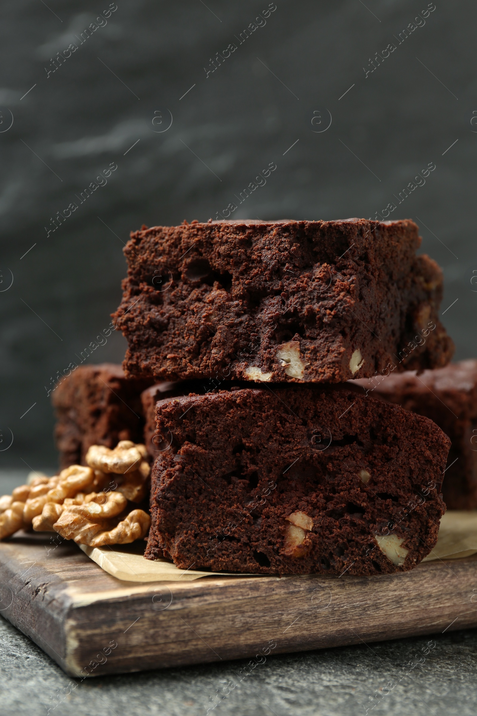 Photo of Delicious chocolate brownies with nuts on grey table, closeup