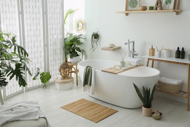 Photo of Stylish bathroom interior with modern tub, houseplants and beautiful decor. Home design