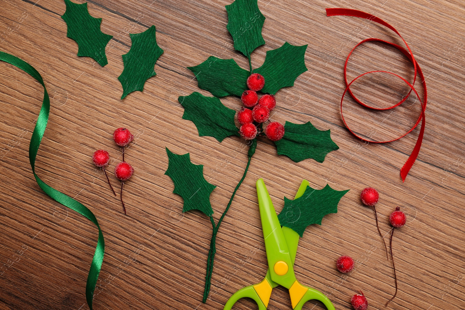 Photo of Set of instruments and materials for making mistletoe branch on wooden table, flat lay