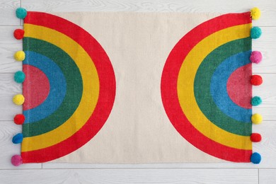 Stylish rug with rainbow on floor, top view