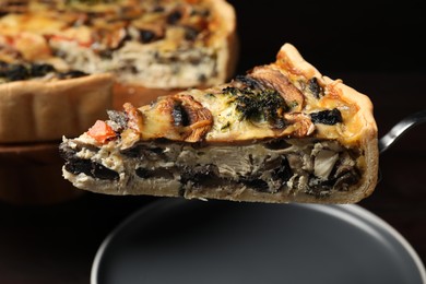 Photo of Piece of delicious quiche with mushrooms on spatula over plate, closeup