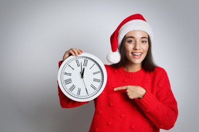 Photo of Woman in Santa hat with clock on white background, space for text. New Year countdown