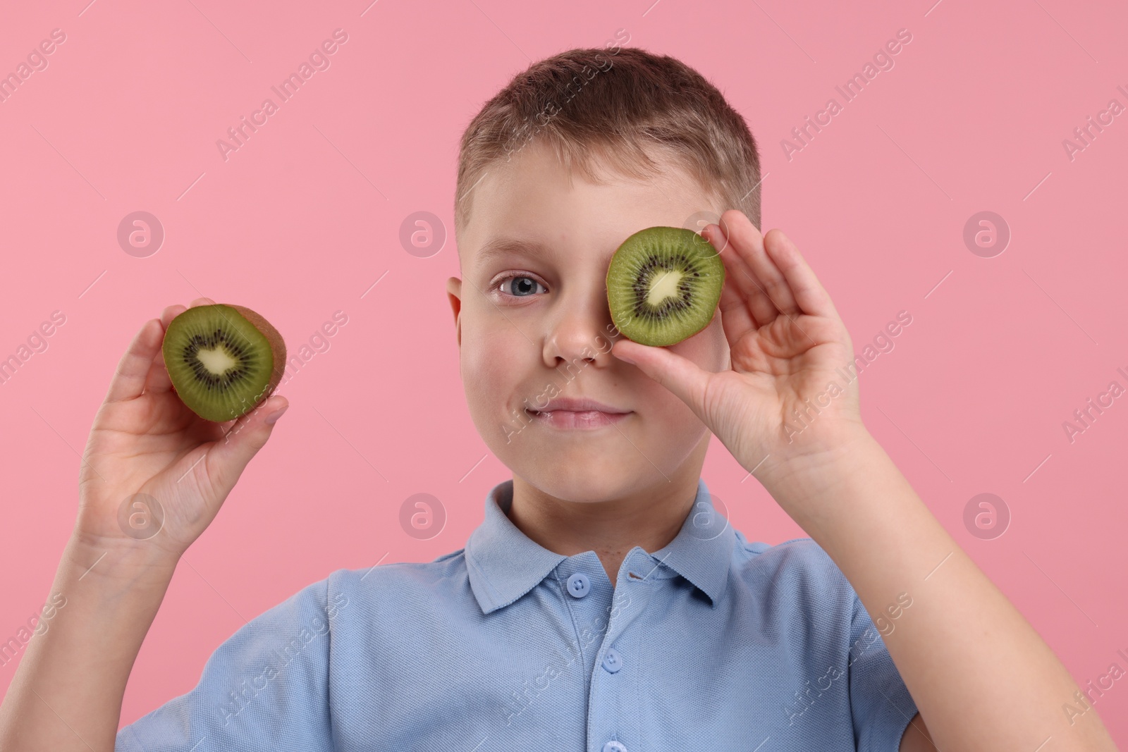 Photo of Boy with fresh kiwi on pink background