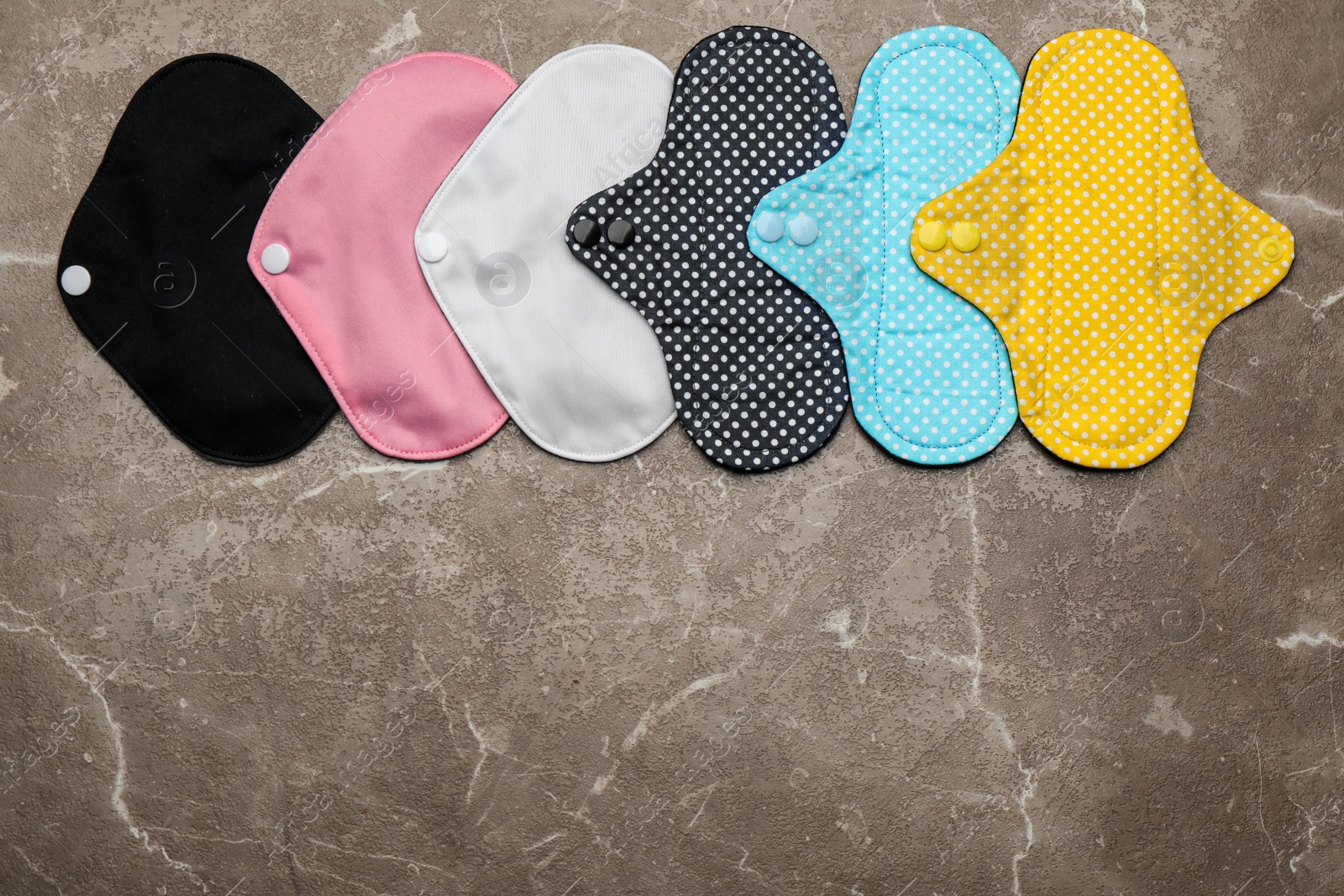Photo of Many reusable cloth menstrual pads on brown table, flat lay. Space for text