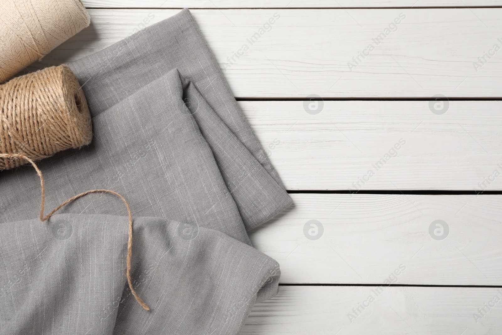 Photo of Hemp cloth and threads on white wooden table, above view. Space for text