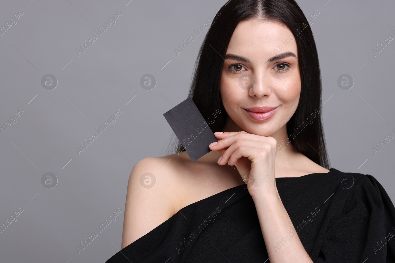 Photo of Woman holding blank business card on grey background. Space for text