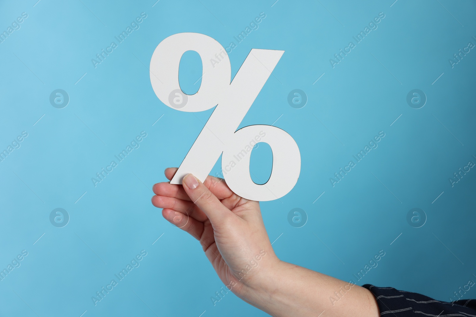 Photo of Woman holding percent sign on light blue background, closeup