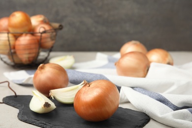 Slate board with ripe onion and slices on grey table, space for text