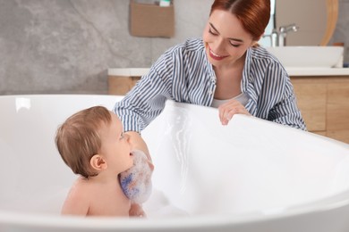 Photo of Mother washing her little baby in tub at home