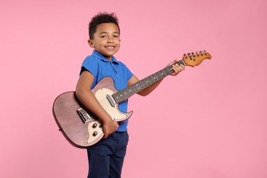 Photo of African-American boy with electric guitar on pink background. Space for text