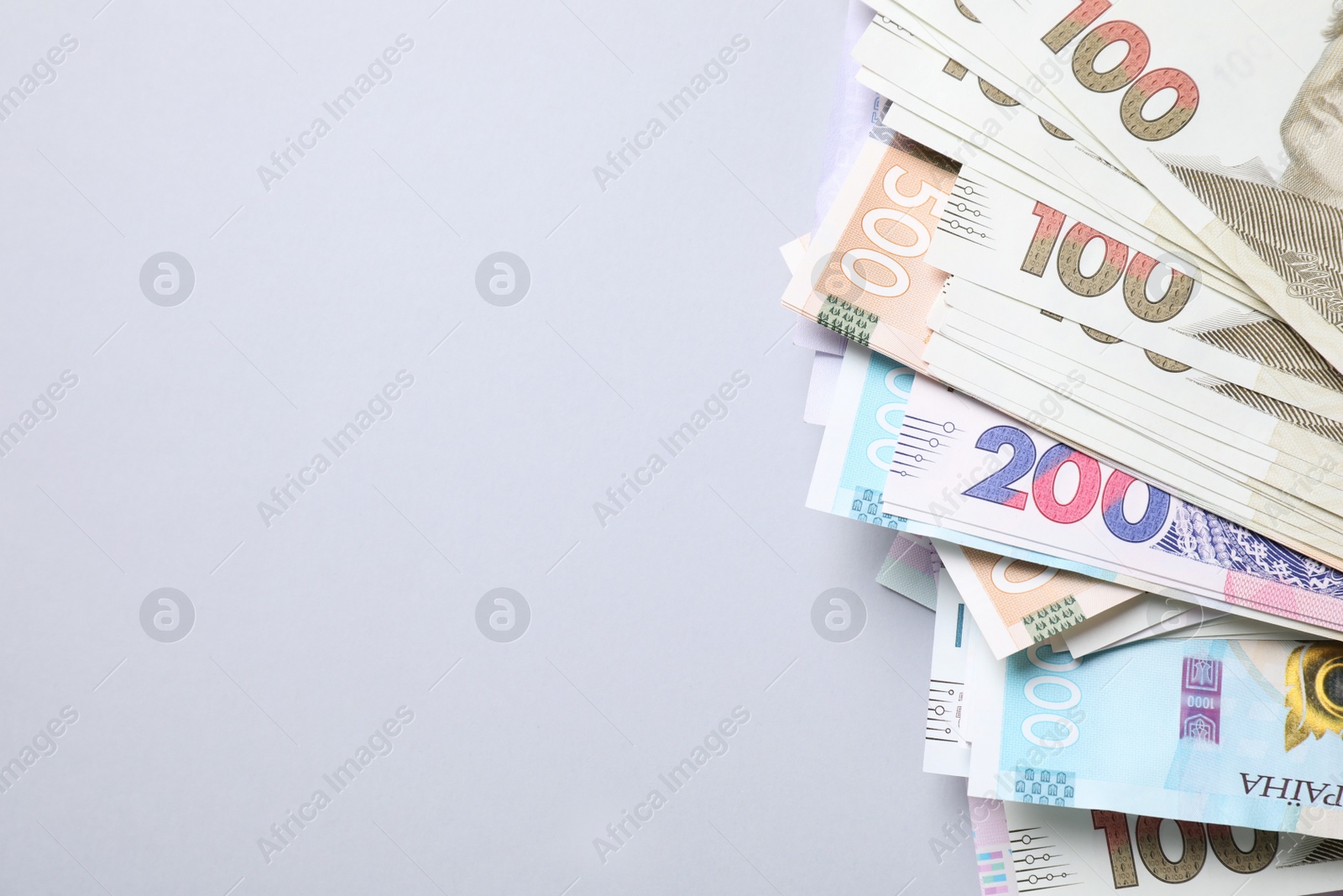 Photo of Ukrainian money on light grey background, flat lay. Space for text