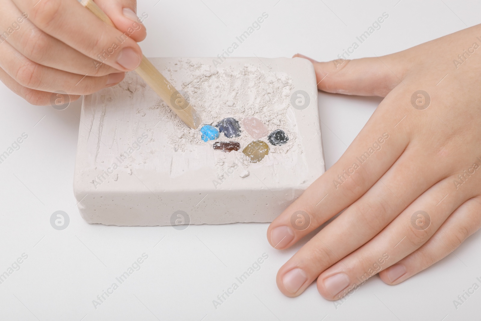 Photo of Child playing with Excavation kit on white background, closeup. Educational toy for motor skills