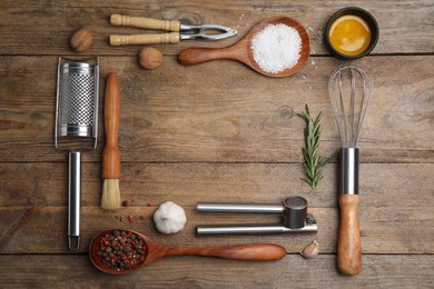 Photo of Frame made of cooking utensils and fresh ingredients on wooden table, flat lay. Space for text
