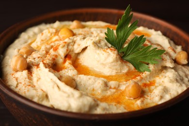 Photo of Bowl of tasty hummus with chickpeas and paprika, closeup