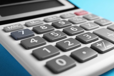 Calculator on light blue background, closeup. Office equipment