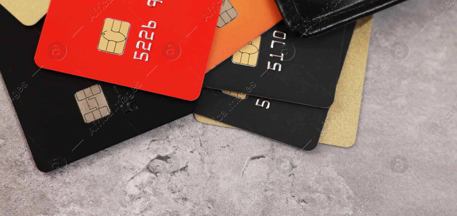 Photo of Pile of different credit cards on grey table, closeup