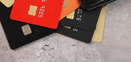 Photo of Pile of different credit cards on grey table, closeup