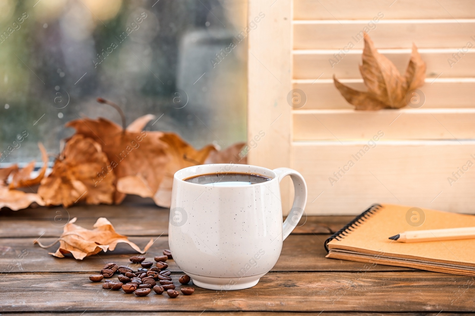 Photo of Composition with cup of hot cozy drink and autumn leaves on windowsill