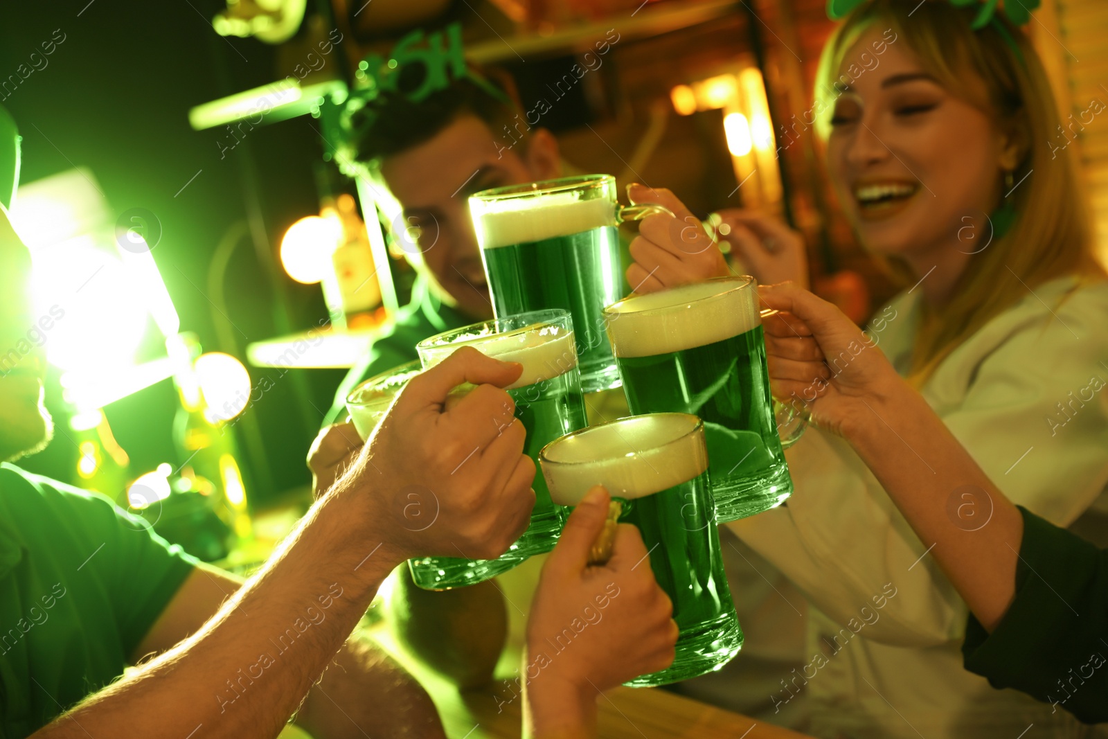 Photo of People with beer celebrating St Patrick's day in pub, focus on hands