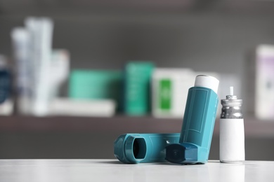 Asthma inhalers on table against blurred background. Space for text