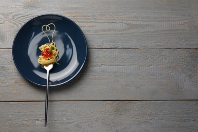 Photo of Heart made with spaghetti and fork on grey wooden table, top view. Space for text