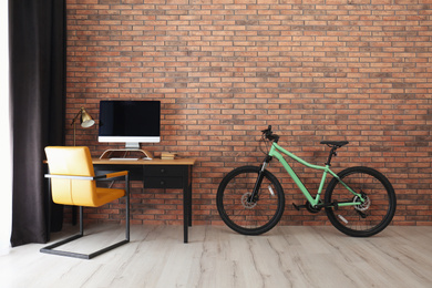 Photo of Stylish room interior with modern green bicycle and workplace