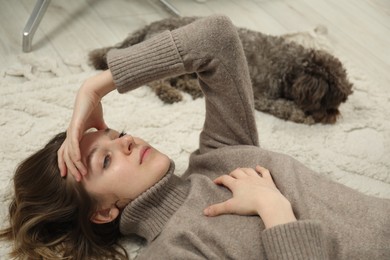 Photo of Sad young woman and her dog lying on floor at home