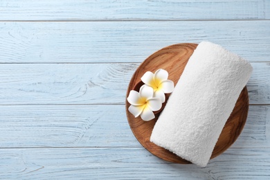 Photo of Plate with flowers and towel on wooden background, top view