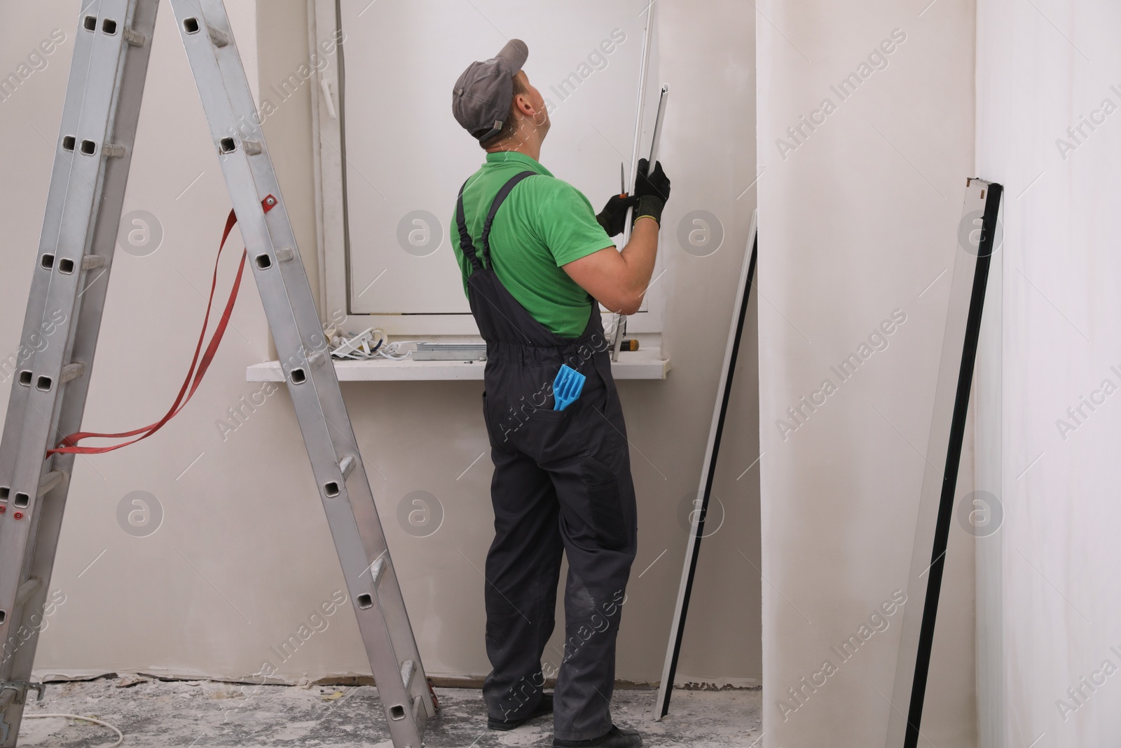 Photo of Worker in uniform installing double glazing window indoors, back view