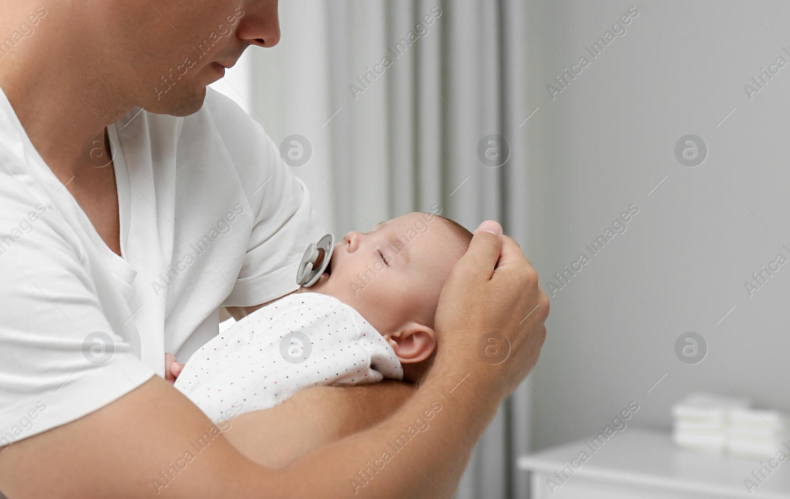 Photo of Father holding his cute sleeping baby at home, space for text