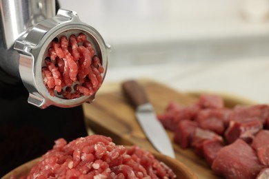 Electric meat grinder with beef on white table, closeup. Space for text