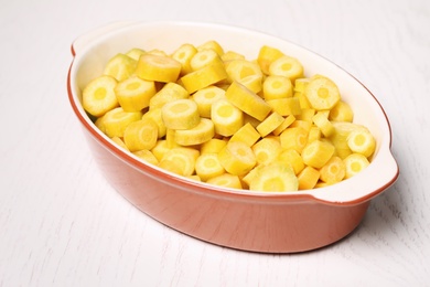 Photo of Raw cut yellow carrot in baking dish on white wooden table, closeup