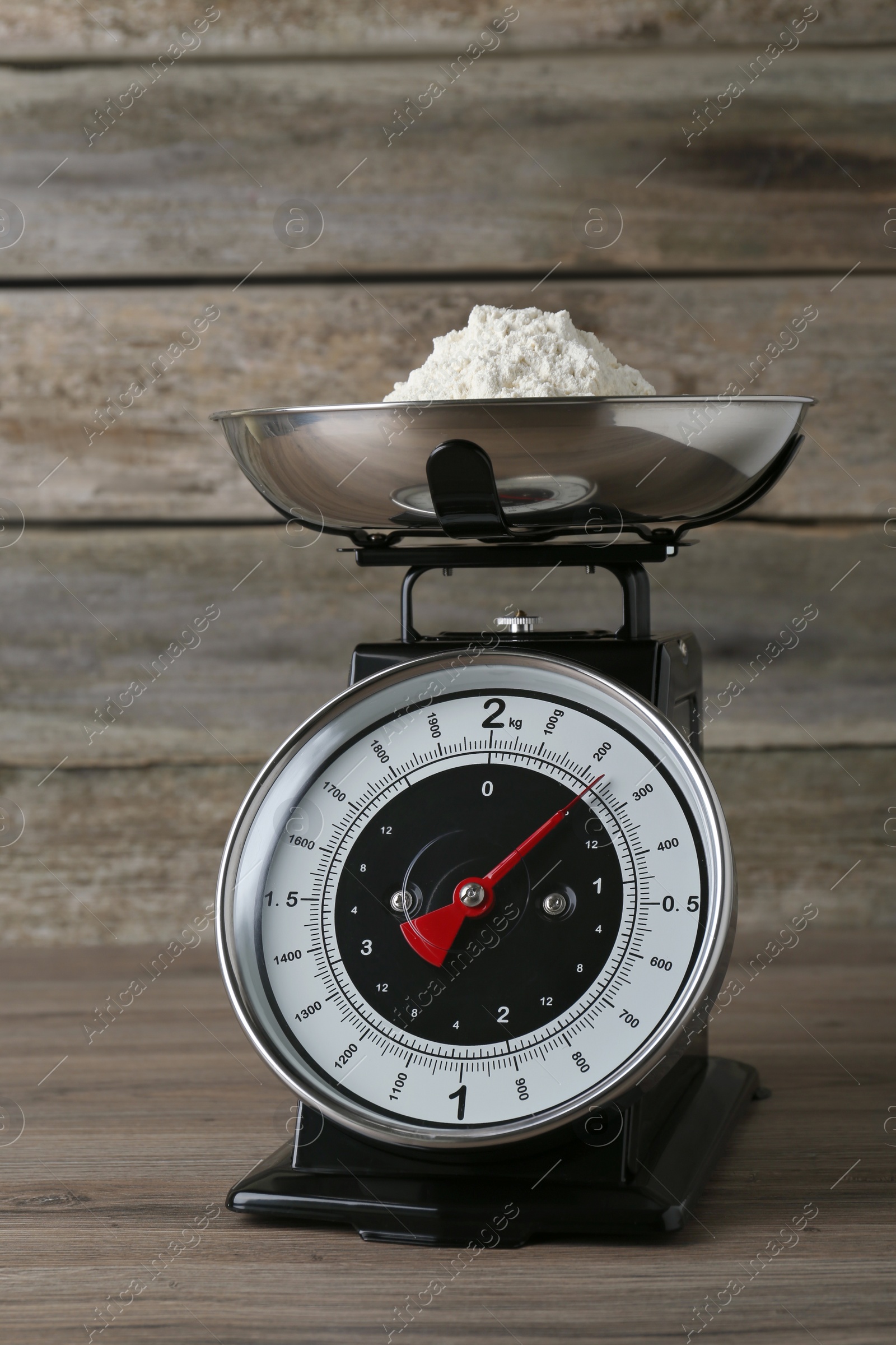 Photo of Kitchen scale with flour on wooden table