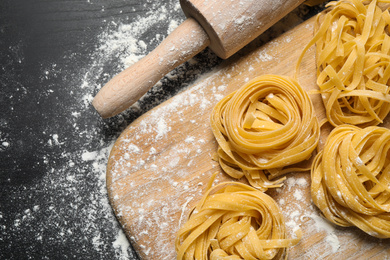 Photo of Tagliatelle pasta on wooden board, flat lay