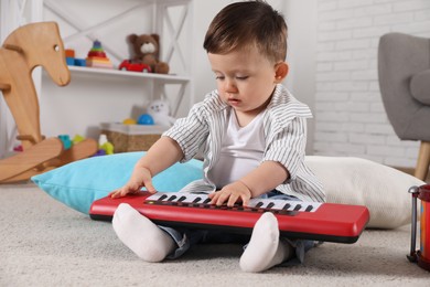 Photo of Cute little boy playing toy piano at home