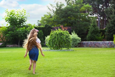 Cute little girl running in green park on summer day