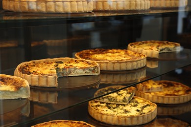 Different delicious quiches on counter in bakery shop, closeup