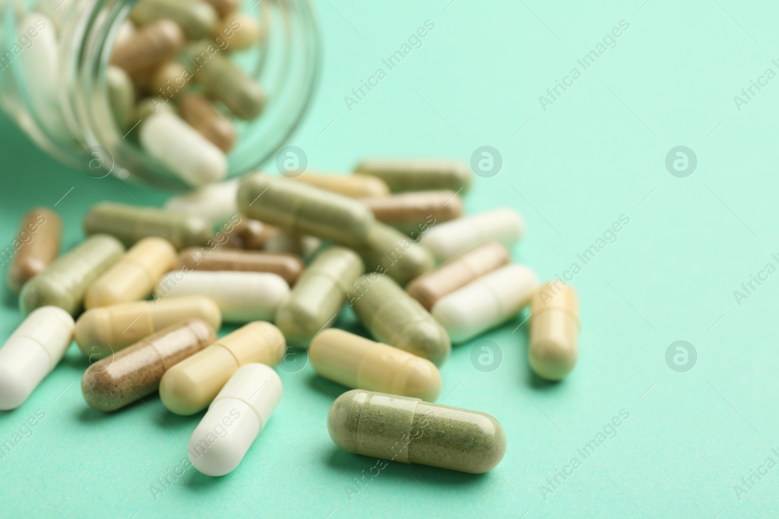 Photo of Vitamin pills on mint color background, closeup