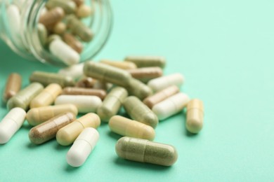 Photo of Vitamin pills on mint color background, closeup