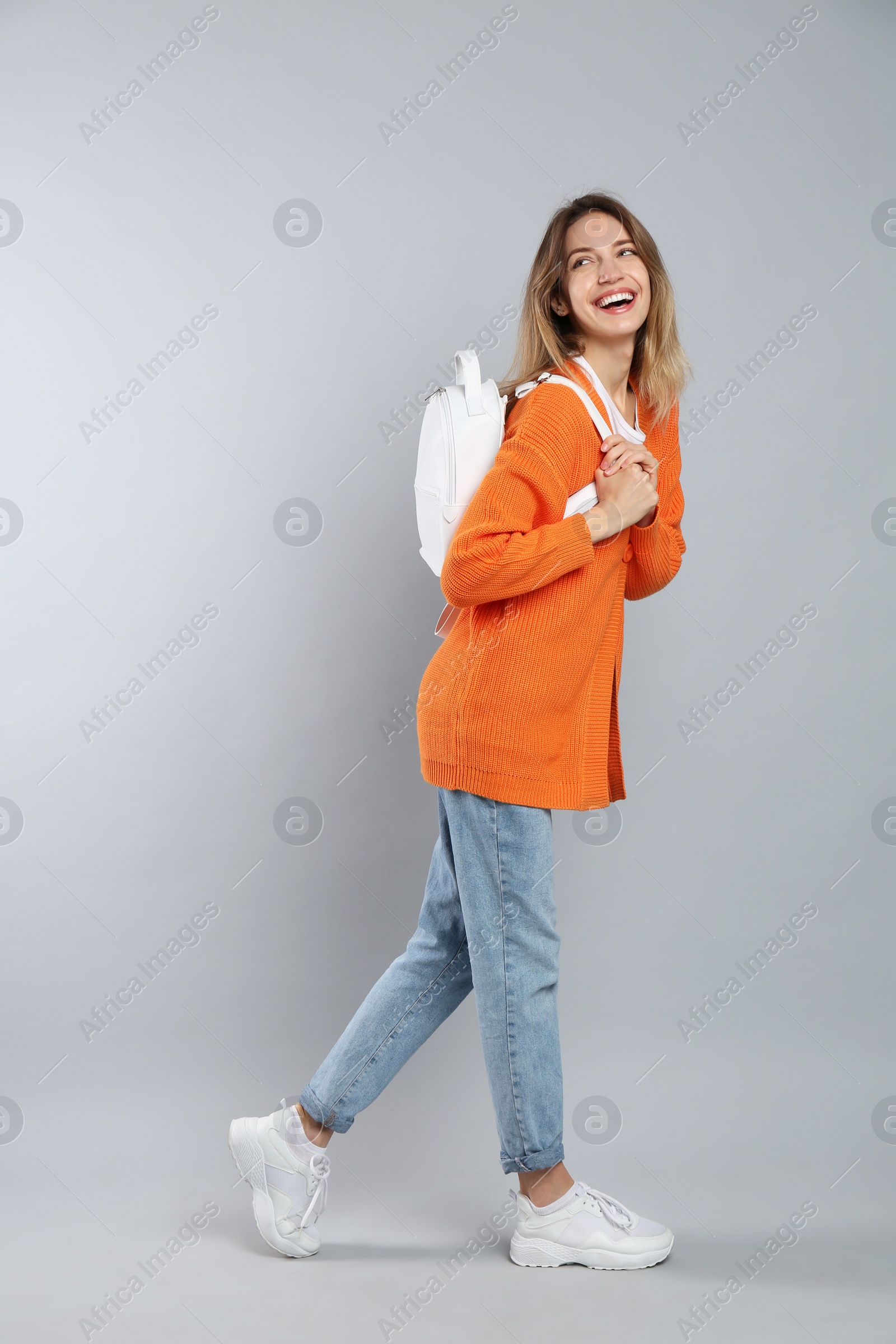 Photo of Happy woman with backpack on light grey background