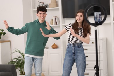 Smiling teenage bloggers dancing while streaming at home