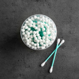 Photo of Plastic container with cotton swabs on grey background, top view