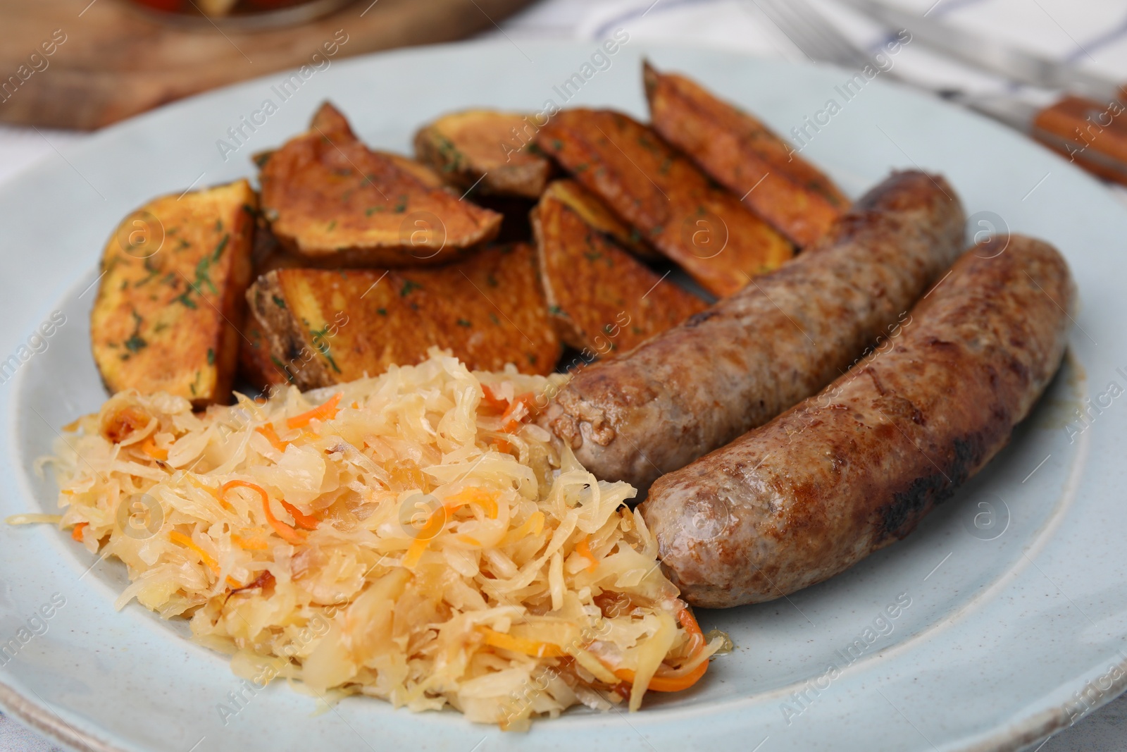 Photo of Plate with sauerkraut, sausages and potatoes on table, closeup