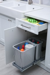 Photo of Open cabinet and drawer with different cleaning supplies in kitchen