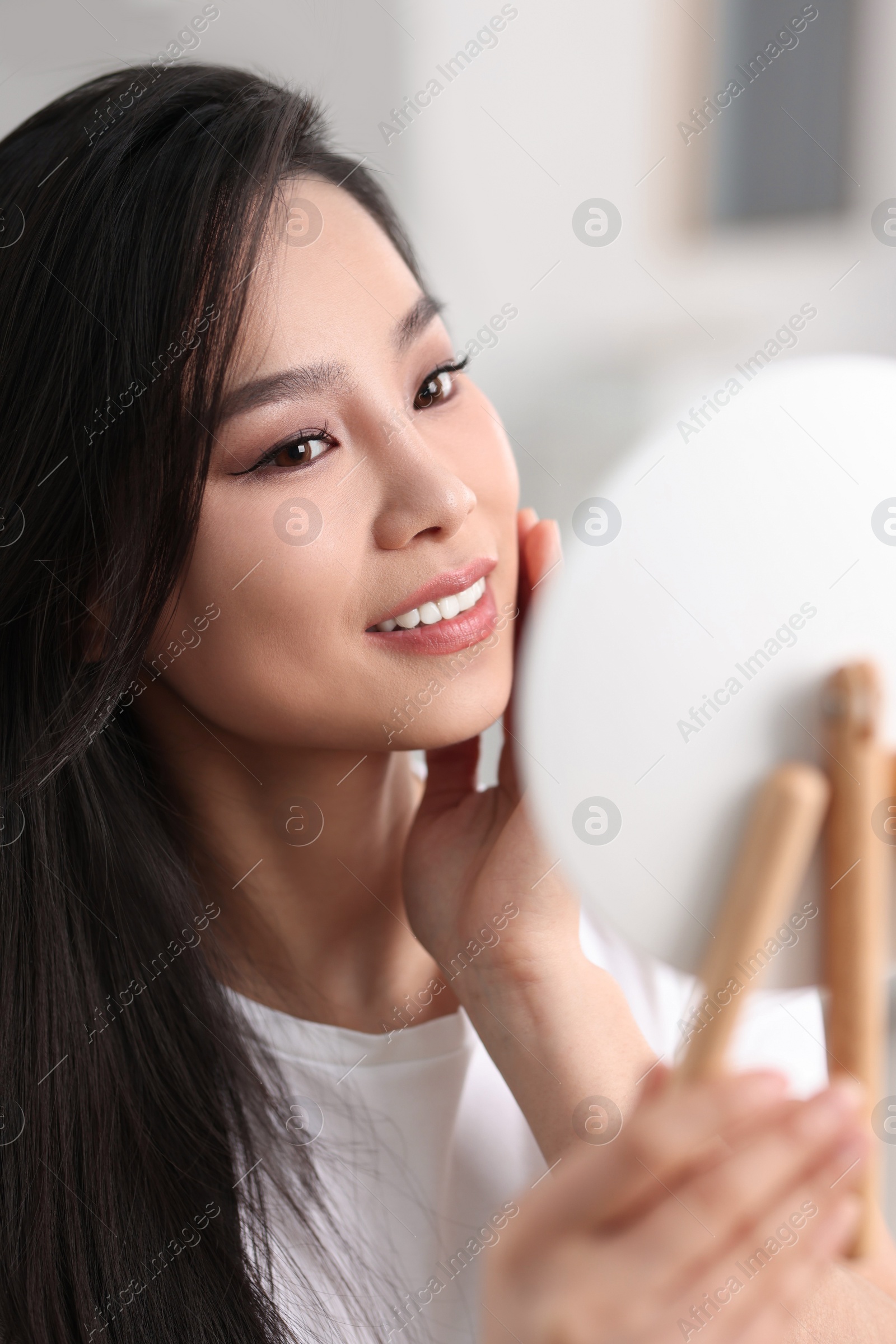 Photo of Woman with perfect skin looking at mirror indoors